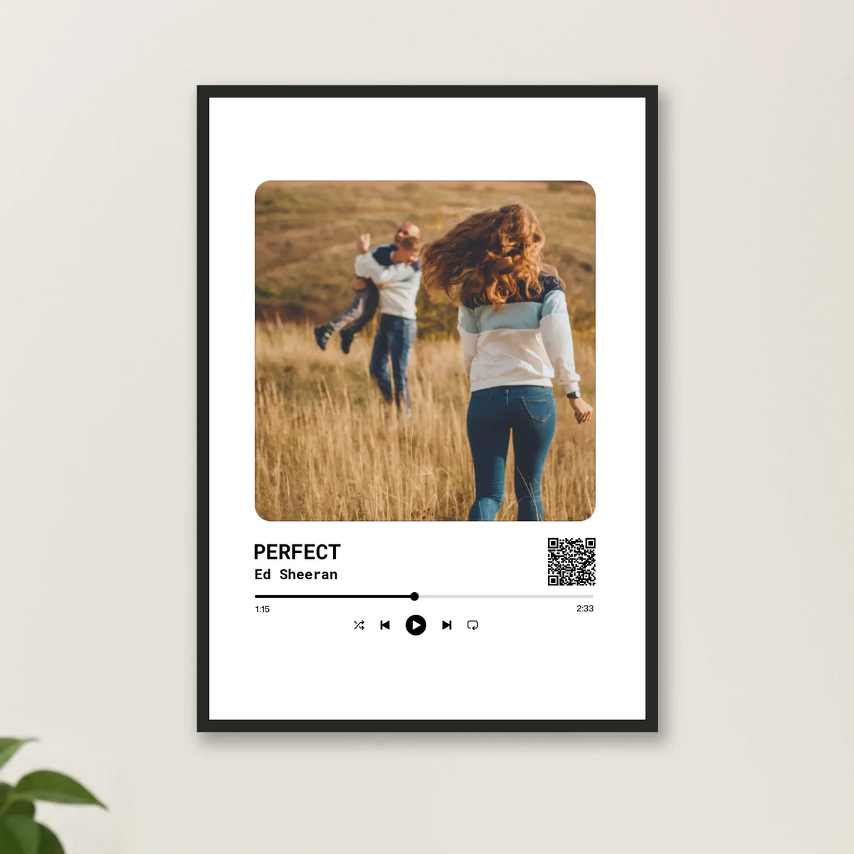 Song-Poster im schwarzen Rahmen an heller Wand mit Pflanze